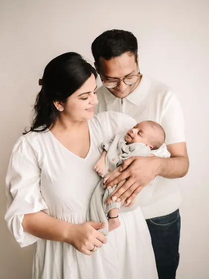 The new family of three, with mom and dad looking down at their precious newborn baby.