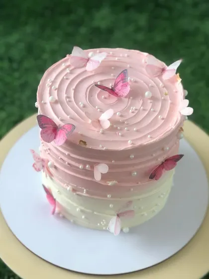 A close-up of the delicate butterfly details on the pink cake.