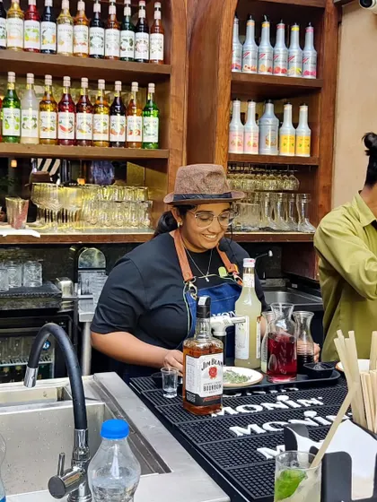 A member of our team smiling as she works behind a fully stocked bar. We are passionate about what we do, and it shows in our service.