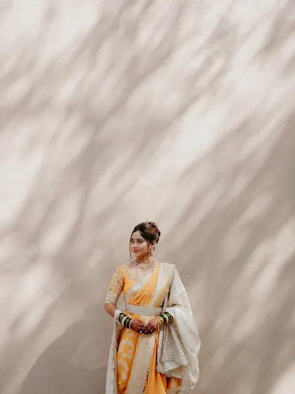 A wide shot capturing the serene beauty of the bride in her complete traditional attire against a simple backdrop.
