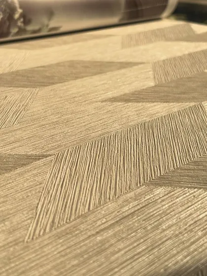 A close-up of a beige geometric wallpaper with a 3D effect. The overlapping shapes and textured lines create a sense of depth, making it a subtle yet impactful choice for a modern bedroom or office.