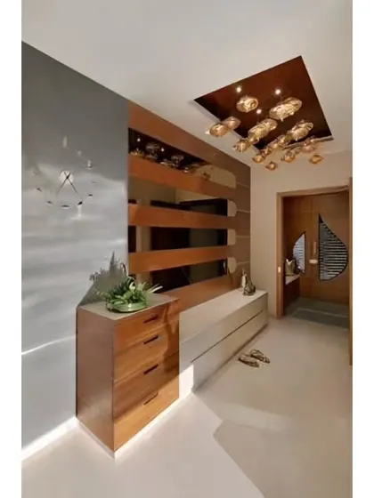A close-up of a modern foyer with a wooden chest of drawers and a sleek white console table against a grey wall with a wooden partition.