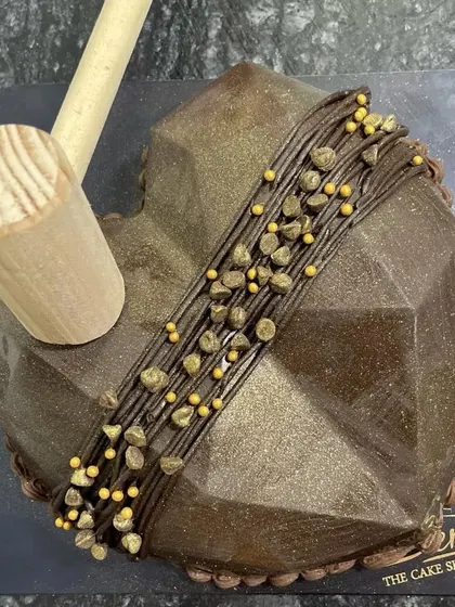 Add some fun to your party with this geometric heart-shaped piñata cake. It comes with a small wooden hammer to smash open the chocolate shell and reveal a surprise filling of candies and treats inside.