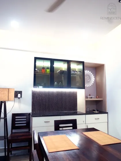 A dining area with a dark wood table and a custom crockery unit featuring fluted paneling and a dedicated pooja nook. The under-cabinet lighting adds a warm glow.