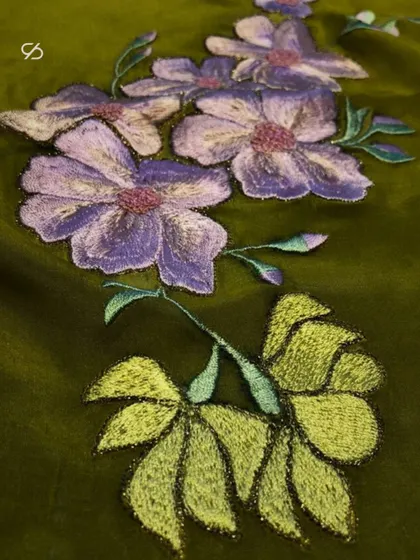Whispering tales of gardens through needle and thread. This image shows a beautiful floral embroidery pattern on an olive green velvet fabric.