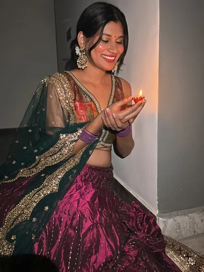 A happy moment during Diwali. The dark green dupatta with heavy gold embroidery provides a beautiful contrast to the magenta and gold of the lehenga.