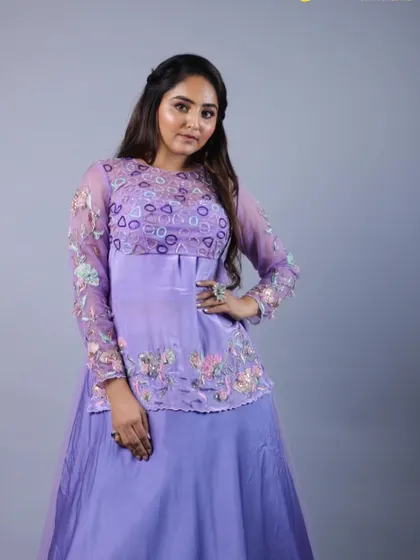 A full-length shot of our purple lehenga with its sheer, long-sleeved overlay. The combination of the solid skirt and the embroidered top creates a balanced and contemporary look.