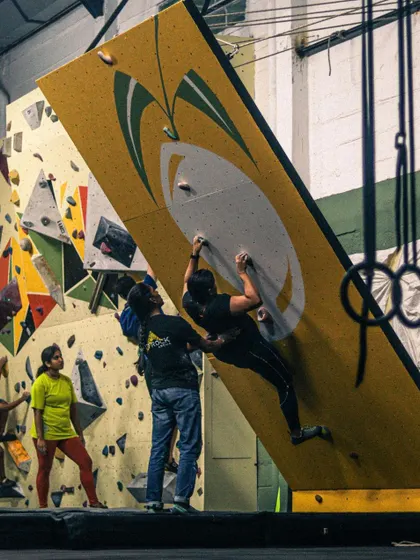 Safety and support are key, even for advanced climbers. Here, a spotter assists a climber on the MoonBoard, ensuring they can push their limits with confidence.