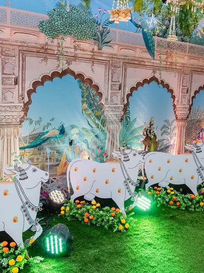 Detail shot of our Pichwai-themed decor, showcasing the hand-painted style wall panels depicting scenes from Vrindavan. The custom-made cow cutouts are placed along the walkway, adding a layer of authenticity and charm to the religious event.