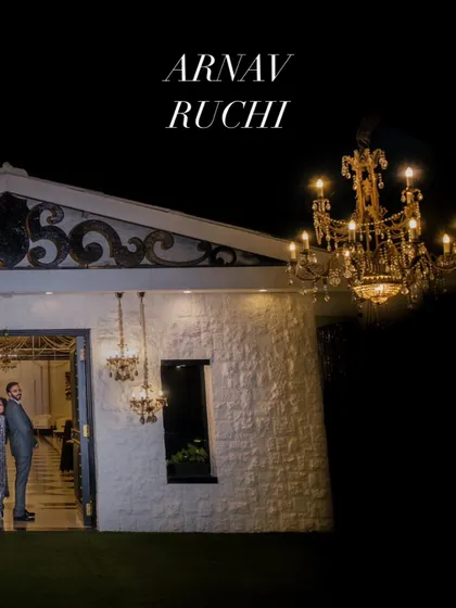 A cinematic portrait of the couple outside their wedding venue at night, framed by the elegant architecture and lighting.