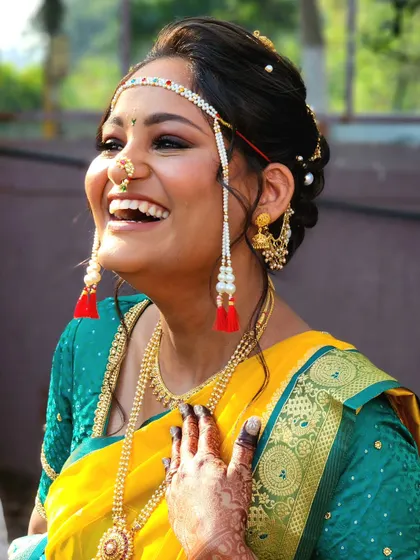 A candid shot capturing the infectious laughter of a happy bride. Her traditional Marathi look is completed with a mundavalya and glowing makeup.