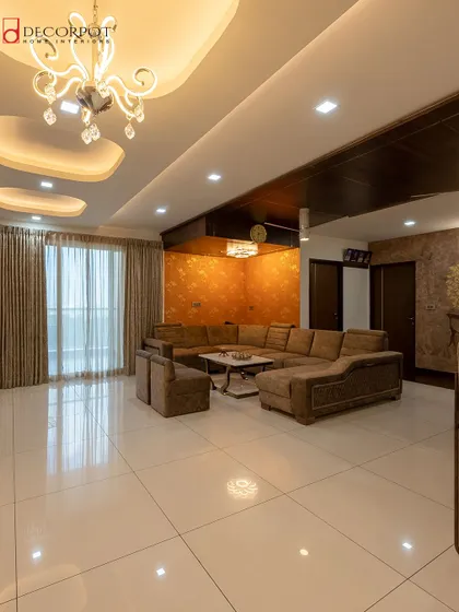 This grand living room is designed for ultimate comfort and style. A large U-shaped sofa provides ample seating, while a textured accent wall and a crystal chandelier create a sense of opulence.
