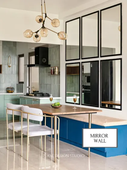 A mirror wall is a fantastic way to enhance a dining space. Here, a grid of black-framed mirrors not only adds a strong graphic element but also reflects light and creates the illusion of a much larger room.