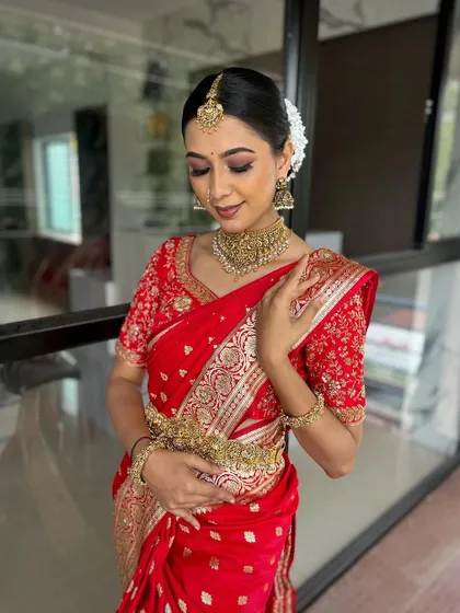 A beautiful profile shot of the model in the red Banarasi saree, showing the elegant hairstyle and the detailed embroidery on the blouse.