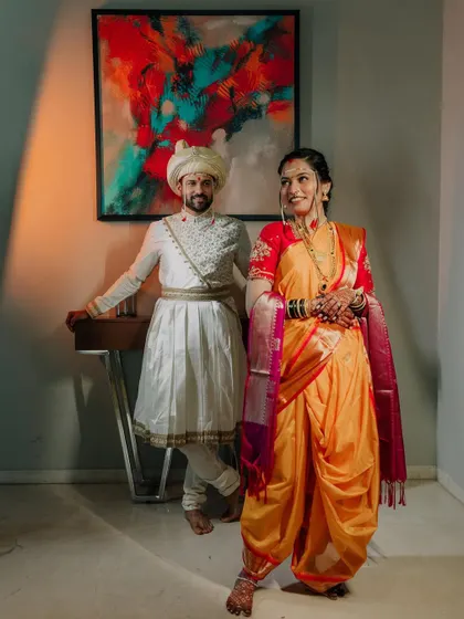 A full-length portrait of the couple, showcasing their coordinated traditional outfits. The bride's nauvari and the groom's Peshwai-style attire are highlighted.