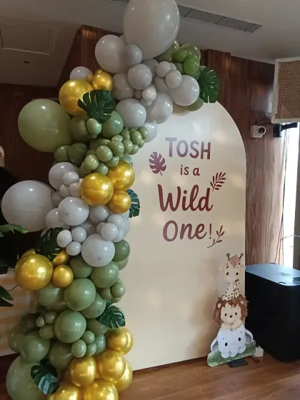 A wider angle of the 'Tosh is a Wild One' setup. The organic balloon garland beautifully frames the custom backdrop, creating a perfect spot for birthday photos.