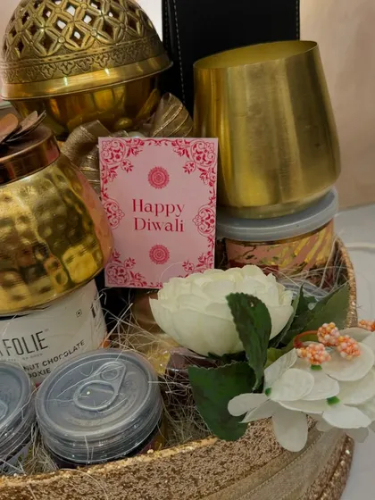 A detail shot of the Glitterati hamper, showing the 'Happy Diwali' card nestled amongst premium coffee, cookies, and other treats. It's all about those small, thoughtful touches.