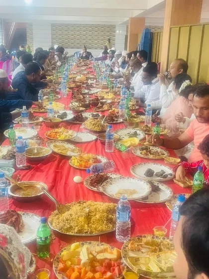 A candid shot of guests enjoying a traditional meal at a 'dawat' in Chitradurga. You can see large platters of biryani being shared, which is the heart of these communal feasts.