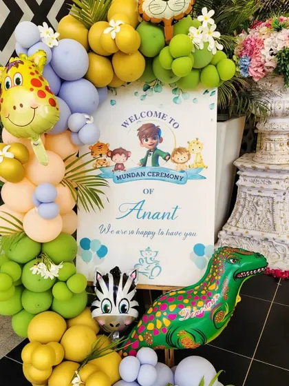 A custom welcome sign for a Mundan ceremony with a fun, kid-friendly theme. The sign is decorated with a colorful balloon arrangement and foil balloons of a giraffe, zebra, and dinosaur.