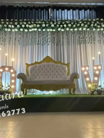 A romantic and elegant anniversary decoration. This setup features a white floral backdrop, an elegant settee, and large "LOVE" marquee letters, creating a perfect ambiance for celebrating a milestone.
