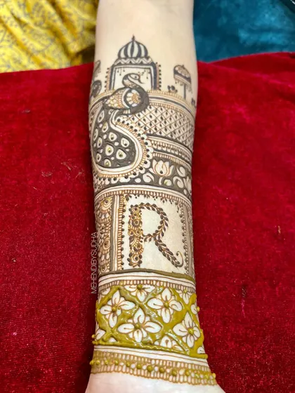 The groom's initial 'R' is crafted with a rope-like texture, surrounded by floral patterns and a majestic peacock, symbolizing beauty and grace.