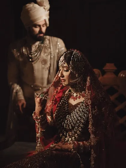 A quiet, intimate portrait of the couple. The bride's stunning red lehenga contrasts beautifully with the groom's ivory sherwani.