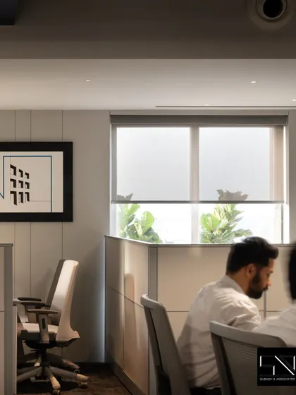 A quiet corner of the office, where clean lines and neutral tones create a focused work environment. The framed abstract art and natural light from the window contribute to a calm and uncluttered atmosphere.