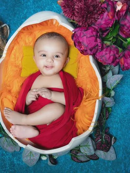 This happy baby is hatching from an egg, ready to explore the world.