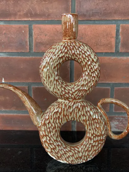 This unique, sculptural piece is a double donut vase, hand-carved with a texture that mimics tree bark.
