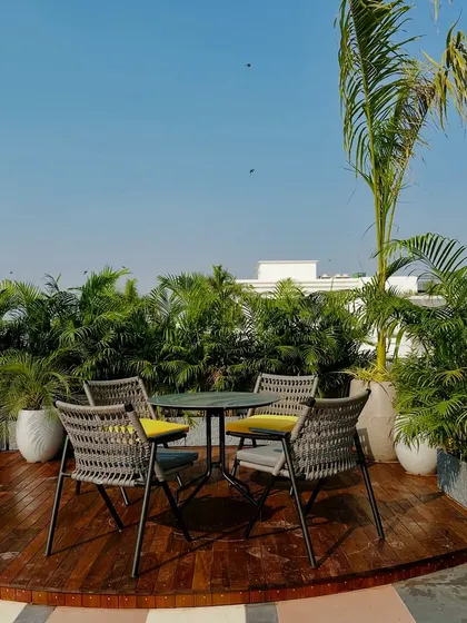 A wider view of the dining area, showing how the circular deck is integrated with the multi-toned tile flooring. The tall palms act as a natural privacy screen.
