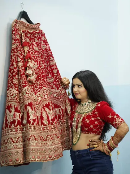 A final pose with the stunning red lehenga before putting it on. The anticipation and excitement are palpable, and her makeup is already flawless.