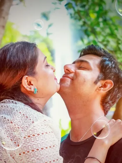 A whimsical pre-wedding photo capturing a sweet kiss on the cheek, surrounded by playful bubbles.