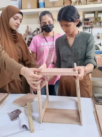 Students assembling a small piece of furniture. This hands-on experience is invaluable for understanding how designs translate into real-world objects.