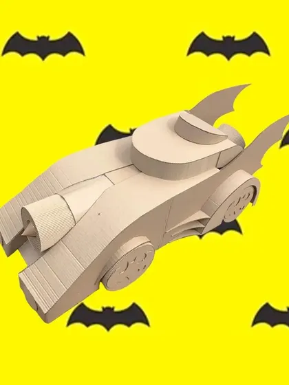 To the Batmobile. This unpainted cardboard Batmobile was designed for a superhero-themed activity. It's a perfect example of a custom build that can be used as a prop or as part of a 'Paint & Play' station.
