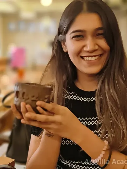 A smiling student holds up the textured cup she made. Our workshops are perfect for anyone looking to try a new creative hobby in a social setting.