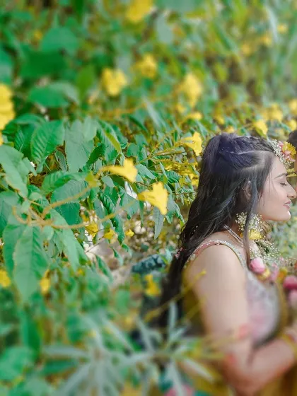 An intimate close-up of the couple surrounded by yellow flowers and greenery, capturing a quiet moment of connection during their Haldi celebrations.