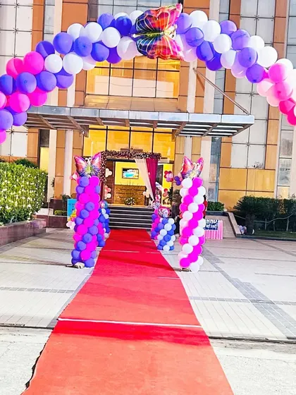 A grand entrance for a birthday party, featuring a red carpet and a large balloon arch with butterfly accents. This sets a festive tone from the moment guests arrive.