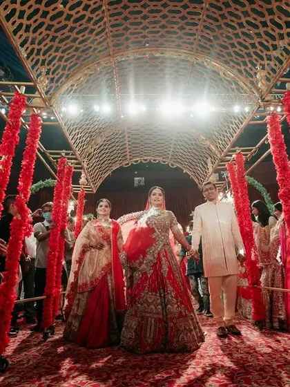 A powerful shot of the bride walking with her parents, flanked by attendants, creating a regal and supportive procession towards the mandap.