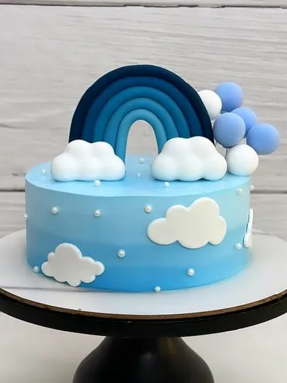 A beautiful blue ombre cream cake with a rainbow and fluffy fondant clouds. It feels like a perfect slice of a clear winter sky.