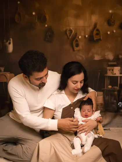 A wider angle of the new family, showing them seated together in the styled studio setting. This shot provides context and showcases the cozy, warm atmosphere of the session.