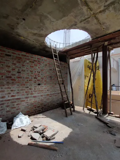 A circular opening for a future skylight in a raw concrete slab, with a simple wooden ladder hinting at the work to come.