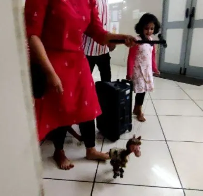A candid moment from a puppetry class where a child learns to handle a marionette. It's a fun challenge that combines coordination and storytelling.