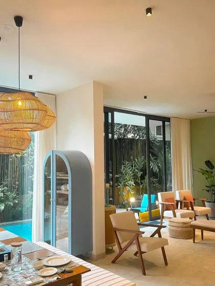 This is a beautiful, open-concept living and dining area with a connection to the outdoors. The use of natural materials like wicker and wood, combined with ample light, creates a relaxed, resort-like feel.