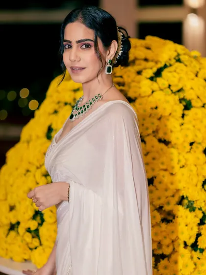 A close-up showing the elegant hairstyle and emerald jewelry, perfectly complementing the white saree and the resort's vibe.
