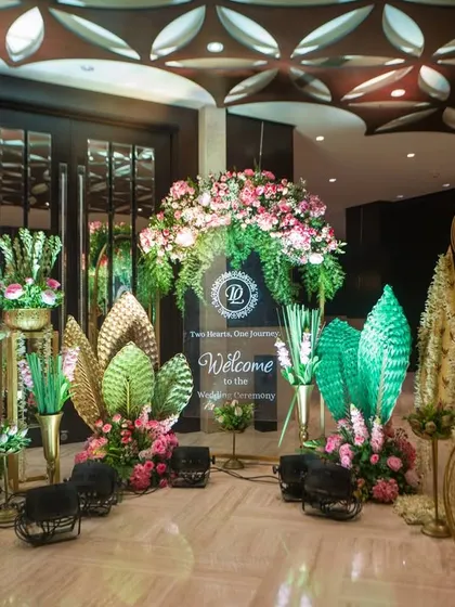 A close-up of the welcome area, showcasing the blend of textures. I used golden lotus-leaf motifs, pink floral arrangements, and custom signage to create a unique and artistic entrance for this Taj Santacruz wedding.