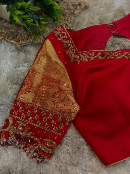 A detailed shot of the sleeve of the red blouse, showcasing the intricate zardosi work and pearl detailing.