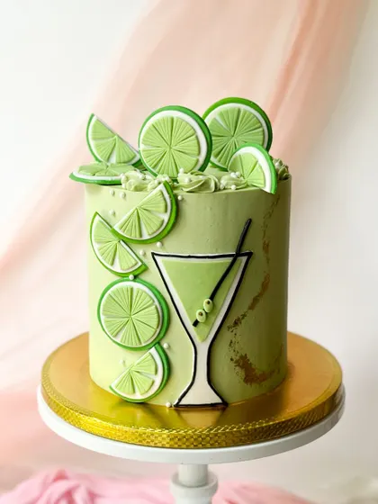A refreshing lime and cocktail themed cake. The vibrant green buttercream is decorated with fondant lime slices and a graphic-style cocktail glass.