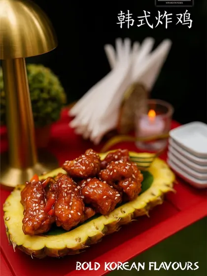 Bold Korean flavors plated with creativity. This dish features crispy chicken coated in a sweet and spicy gochujang sauce, served in a hollowed-out pineapple for a presentation that is both rustic and chic.