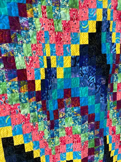 A detail shot of the bright Bargello quilt, highlighting the intricate piecing and the texture from the longarm quilting.