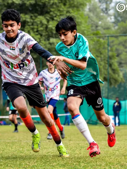Two players from opposing teams in a tight contest for the ball, a common sight in our competitive U13 matches.